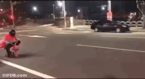 A Person Is Riding A Motorcycle On A Street At Night . GIF