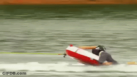 A Person Is Riding A Red And White Raft On A Lake GIF
