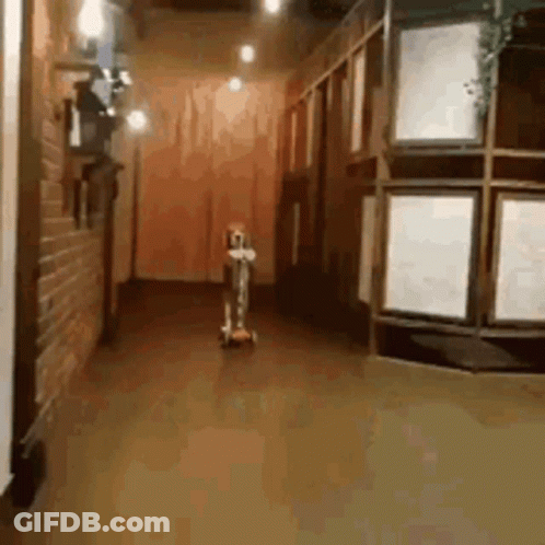 A Person Is Riding A Scooter Down A Hallway GIF