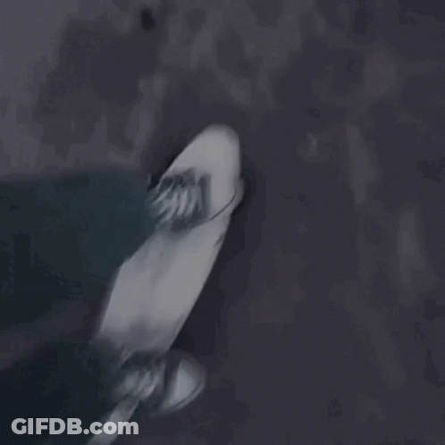 A Person Is Riding A Skateboard Down A Dark Street . GIF