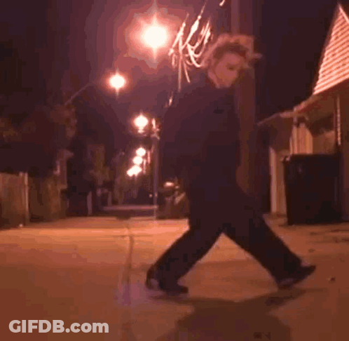 A Person Is Riding A Skateboard Down A Sidewalk At Night . GIF