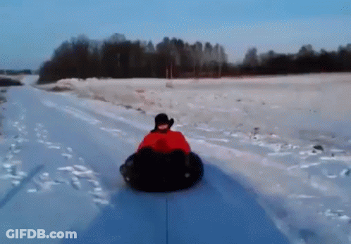 A Person Is Riding Down A Snow Covered Road On A Snow Tube GIF