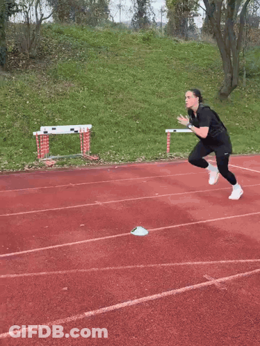 A Person Is Running On A Track With A Stadium In The Background GIF