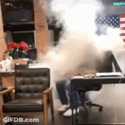 A Person Is Sitting At A Desk In A Room With Smoke Coming Out Of The Window . GIF