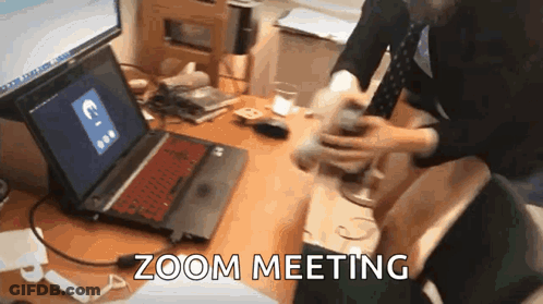 A Person Is Sitting At A Desk With A Laptop On It And The Words Zoom Meeting Written On The Screen . GIF