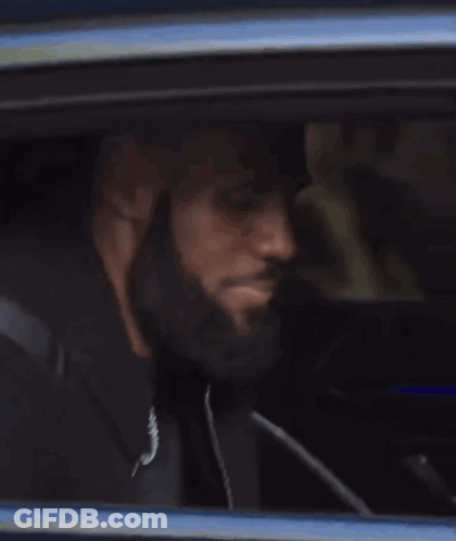 A Person Is Sitting In A Car Looking Out Of The Window . GIF