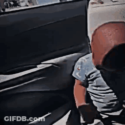A Person Is Sitting In The Back Seat Of A Car Looking Out The Window . GIF