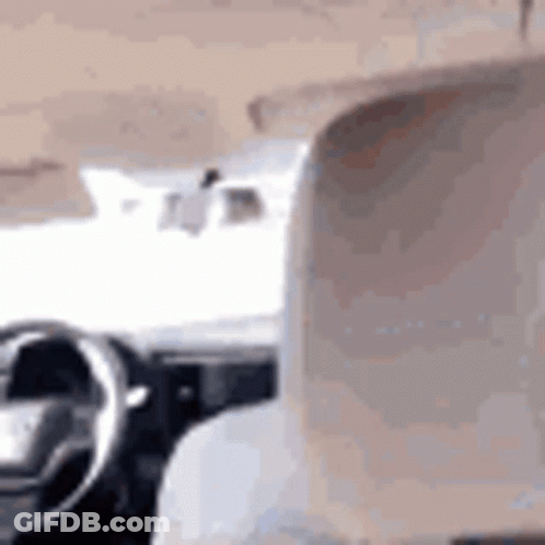 A Person Is Sitting In The Driver 'S Seat Of A Car And Looking Out The Window . GIF