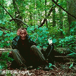 A Person Is Sitting In The Woods With Their Hands On Their Head GIF
