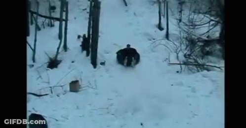 A Person Is Sliding Down A Snow Covered Hill On A Sled . GIF