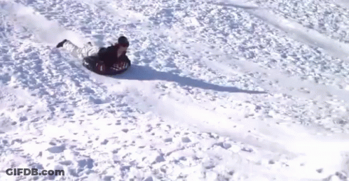 A Person Is Sliding Down A Snowy Hill On A Snow Tube GIF