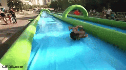 A Person Is Sliding Down An Inflatable Water Slide In A Park GIF