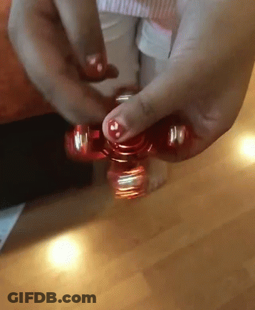 A Person Is Spinning A Red Fidget Spinner In Their Hand GIF