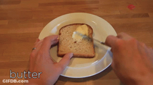 A Person Is Spreading Butter On A Piece Of Bread GIF