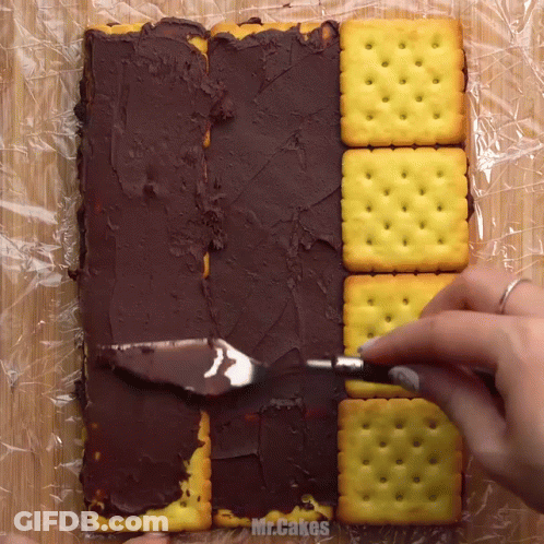 A Person Is Spreading Chocolate Icing On Crackers With The Words Mr.cakes Visible GIF