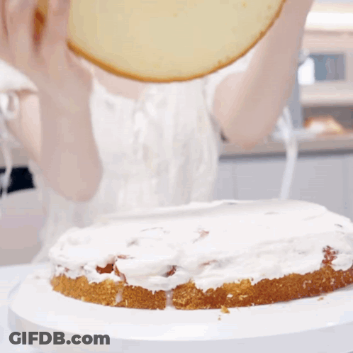 A Person Is Spreading Frosting On A Cake On A Plate GIF