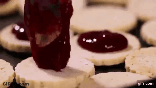A Person Is Spreading Jam On A Cookie . GIF