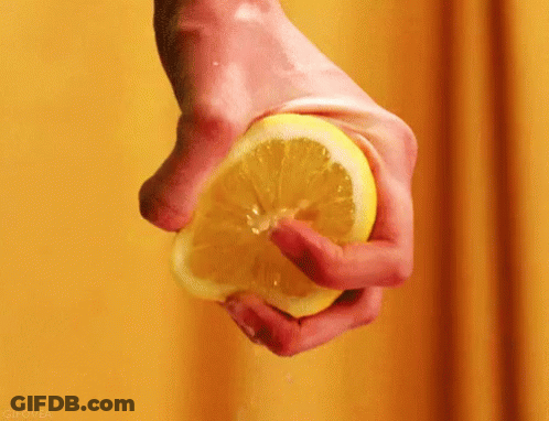 A Person Is Squeezing A Lemon In Their Hand . GIF