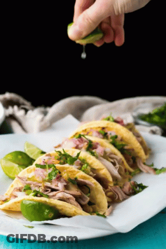 A Person Is Squeezing A Lime Over A Stack Of Tacos GIF