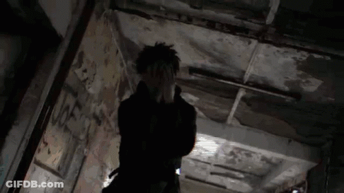 A Person Is Standing In A Dark Hallway With Their Hands On Their Face . GIF