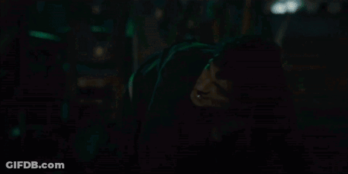 A Person Is Standing In A Dark Room With A Green Light Behind Them GIF