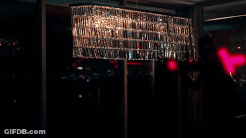 A Person Is Standing In A Dark Room With A Red Light Behind Them GIF