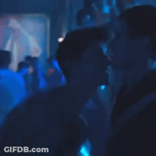 A Person Is Standing In A Dark Room With Blue Lights Behind Them GIF