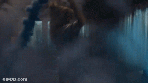 A Person Is Standing In A Dark Room With Smoke Coming Out Of The Window . GIF