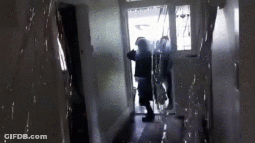 A Person Is Standing In A Hallway With A Door Open GIF