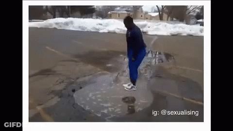 A Person Is Standing In A Puddle Of Water On The Side Of A Road . GIF