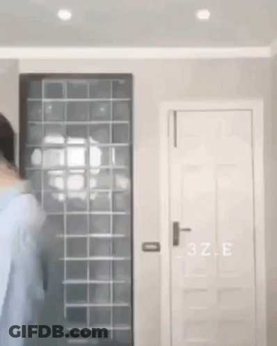 A Person Is Standing In A Room With A Door And A Window . GIF