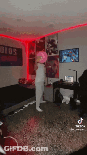 A Person Is Standing In A Room With A Pink Hat On . GIF