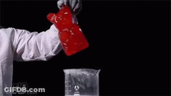 A Person Is Standing In Front Of A Glass Filled With Liquid And Smoke . GIF