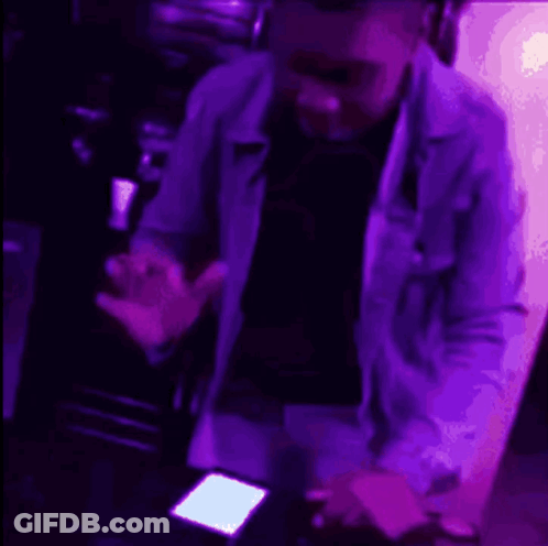 A Person Is Standing In Front Of A Purple Light . GIF