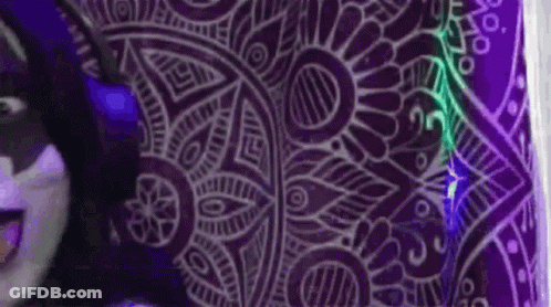 A Person Is Standing In Front Of A Purple Wall With A Purple Pattern On It . GIF