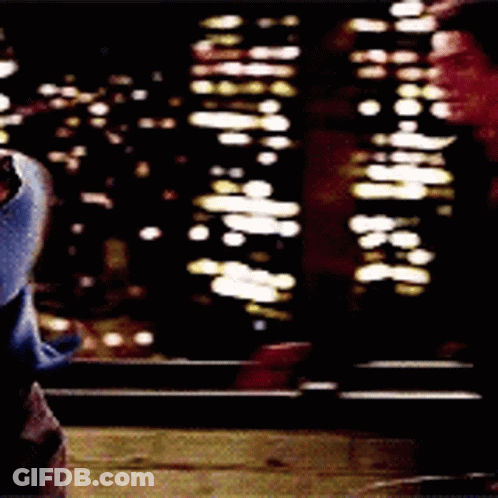 A Person Is Standing In Front Of A Window At Night Looking Out At The City Lights . GIF