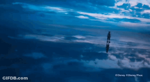 A Person Is Standing In The Middle Of A Cloudy Sky And Their Reflection Is In The Clouds GIF