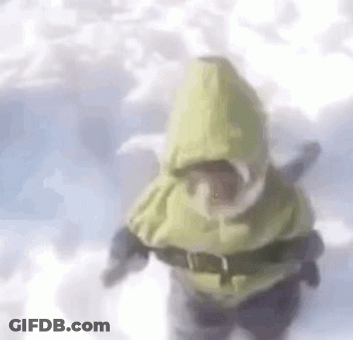 A Person Is Standing In The Snow Wearing A Yellow Hooded Jacket And Goggles . GIF