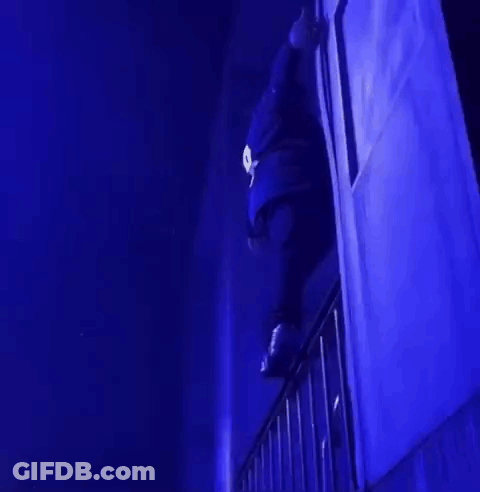 A Person Is Standing On A Balcony In A Dark Room With Blue Lights . GIF