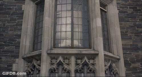 A Person Is Standing On A Balcony With A Stained Glass Window GIF