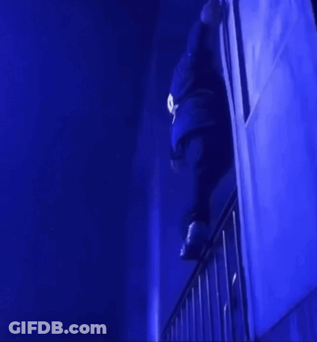 A Person Is Standing On A Railing In A Dark Room With Blue Lights GIF