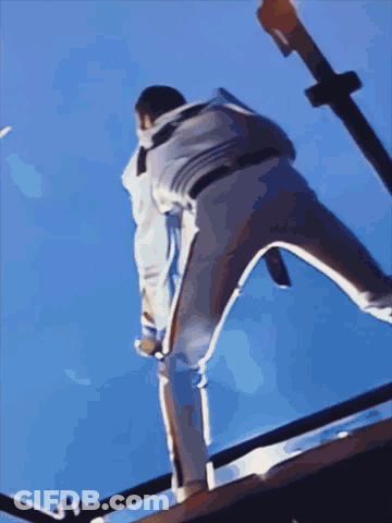 A Person Is Standing On A Railing With A Blue Sky Behind Them GIF