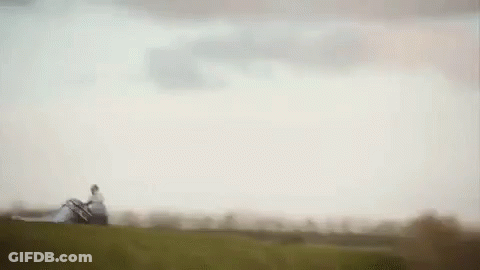 A Person Is Standing On Top Of A Grassy Hill Holding A Large Piece Of Paper . GIF