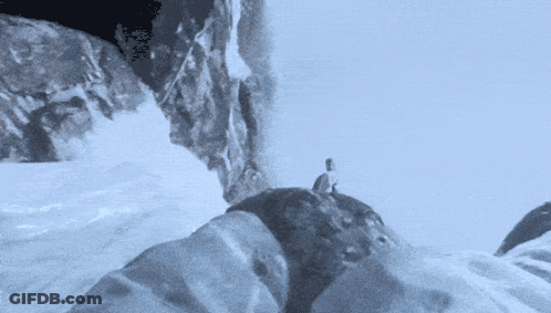 A Person Is Standing On Top Of A Snowy Mountain GIF