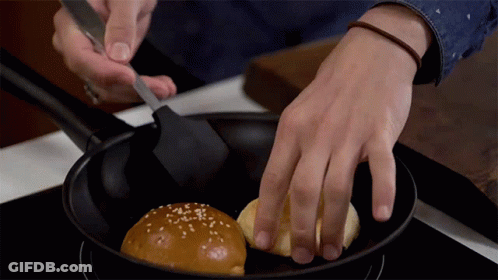 A Person Is Stirring A Hamburger Bun In A Frying Pan GIF