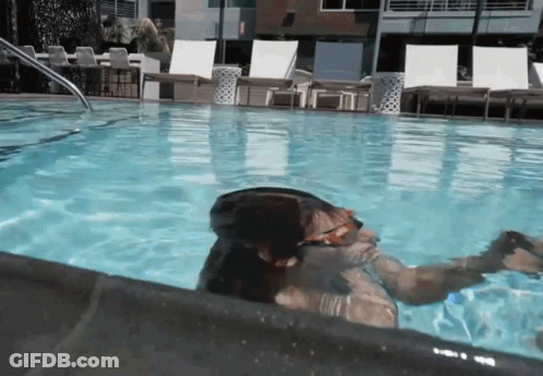 A Person Is Swimming In A Pool With A Reflection Of A Building In The Water GIF