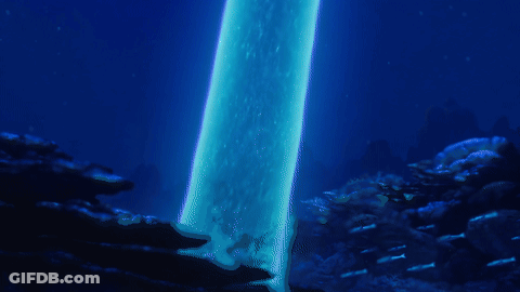 A Person Is Swimming In The Ocean With A Blue Light Coming Out Of The Water GIF
