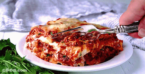 A Person Is Taking A Bite Of Lasagna With A Silver Fork GIF