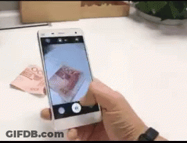 A Person Is Taking A Picture Of A Stack Of Money With A Cell Phone GIF