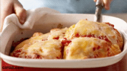 A Person Is Taking A Piece Of Pizza Out Of A Casserole Dish With A Fork GIF